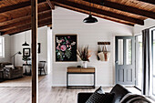 Offener Wohnbereich mit weißen Wänden und rustikaler Holzdecke