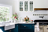 Renovierte Landhausküche mit weißer Fliesenwand und petrolfarbenen Unterschränken