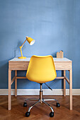 Yellow, classic swivel chair at small desk with yellow lamp