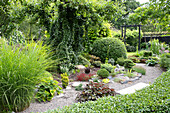 Diversely planted and well-maintained garden with gravel path and pergola