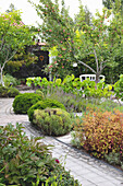 Winding garden path with varied planting and white bench seat