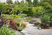 Diversely planted garden with gravel path and bench
