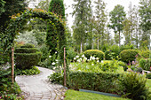 Garden path through well-tended garden with boxwood hedges and flower beds