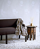 Brown sofa with striped throw on white shag pile carpet and Moroccan carved side table