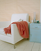 Detail eines modernen Wohnzimmers, weiß gepolsterter Sessel, bemalter Schrank, bemalte Dielen