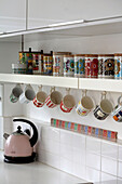 Storage containers and cups on shelf above kettle