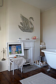 Wall mounted metal swan in bathroom with roll top bath