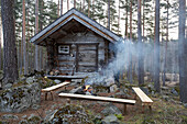 Offenes Feuer vor einer Blockhütte im Wald von Svartadalen, Schweden