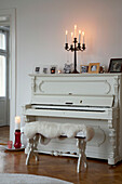 Lit candles on white painted piano in 20th century Stockholm apartment