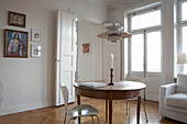 Lit candle on wooden table with pendant light and religious iconography in 20th century Stockholm apartment