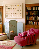 A traditional living room framed butterflies above a painted screen with swallows wooden bookshelf upholstered armchair