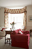 Rotes Sofa und Fenster mit floral gemusterten Vorhängen und Kassettendecke in Arundel, West Sussex