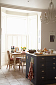 Blue painted kitchen storage and table at sunlit window in Arundel, West Sussex