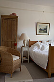 Holzkleiderschrank mit Rattansessel in einem Schlafzimmer in Arundel, West Sussex