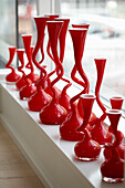 Red designer vases in row on window sill