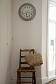 Uhr über einem Holzstuhl mit Korb
