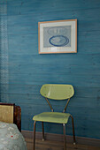 Grüner Stuhl neben dem Bett in einem blau gestrichenen Zimmer