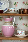 Pink jug with chinaware on wooden shelving