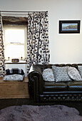Floral patterned curtains and black Chesterfield sofa