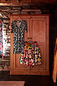 Dress and skirt hang on wooden wardrobe