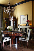 Silberner Kandelaber über gestreiften Esszimmerstühlen am Holztisch im Haus eines Londoner Modedesigners