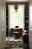 Wooden desk between bookshelves at window of London home