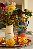 Cut flowers with mini-squash and lit candles in Norfolk beach house, UK
