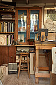 Glass fronted cabinet in artist's studio of Brighton home, Sussex, UK