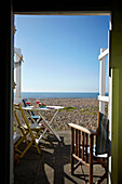View through doorway of beach hut to shingle beach on West Sussex coastline, England, UK