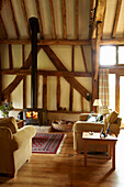 Wohnzimmer mit Holzbalken und Holzofen in einem Haus in West Sussex, England, UK