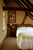Double bed in room with beamed ceiling in West Sussex home, England, UK