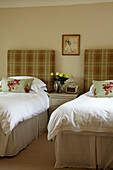 Schlafzimmer mit zwei Einzelbetten, Dekokissen mit Rosenmotiv und Rosenstrauß auf Nachtschrank in Haus in West Sussex, England, UK