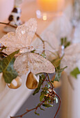A detail of a Christmas decoration in the shape of a butterfly trailing ivy leaves