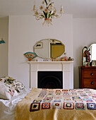 Double bed with crochet bedspread in front of fireplace in traditional style bedroom