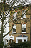 The exterior of a traditional Victorian terraced house with a tree in the foreground