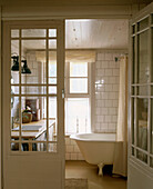Country style bathroom with white tiles and period free standing bathtub