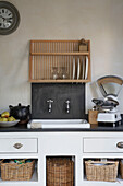 Plate rack above sink set in storage unit with wicker baskets