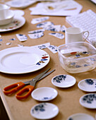 A detail of white tableware being decorated with decoupage scissors