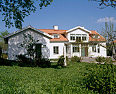 An exterior view of traditional country style white house with red roof