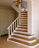A country style staircase leading upstairs with wardrobe behind it