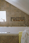 Detail of modern bathroom with a bath tiled walls and slopping ceiling