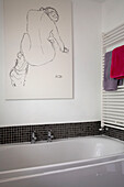 Detail eines modernen Badezimmers mit schwarz-weißem Poster und Handtüchern auf einem Ständer