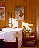 Bedroom with wood panelled walls and bed with floral pattern linen