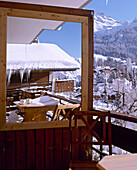Blick vom Balkon eines schweizer Chalets auf schneebedeckte Berge
