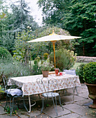 Wrought iron chairs at table with parasol on paved parasol