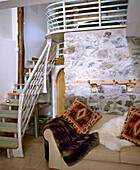 Upholstered sofa in front of exposed stone walls next to staircase