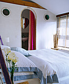 Double bed in white bedroom with archway to ensuite bathroom