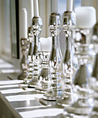 Silver candlesticks in a row on painted window sill