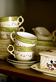 A detail of decorative teacups and saucers set on a shelf
