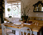 Ein traditionelles Esszimmer mit Holztisch und Stühlen, dekoriert mit Pflanzen, Zweigen und Zapfen